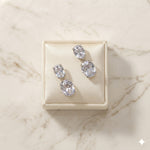 Pair of Josephine silver-finish two-stone drop earrings on a cream jewelry display