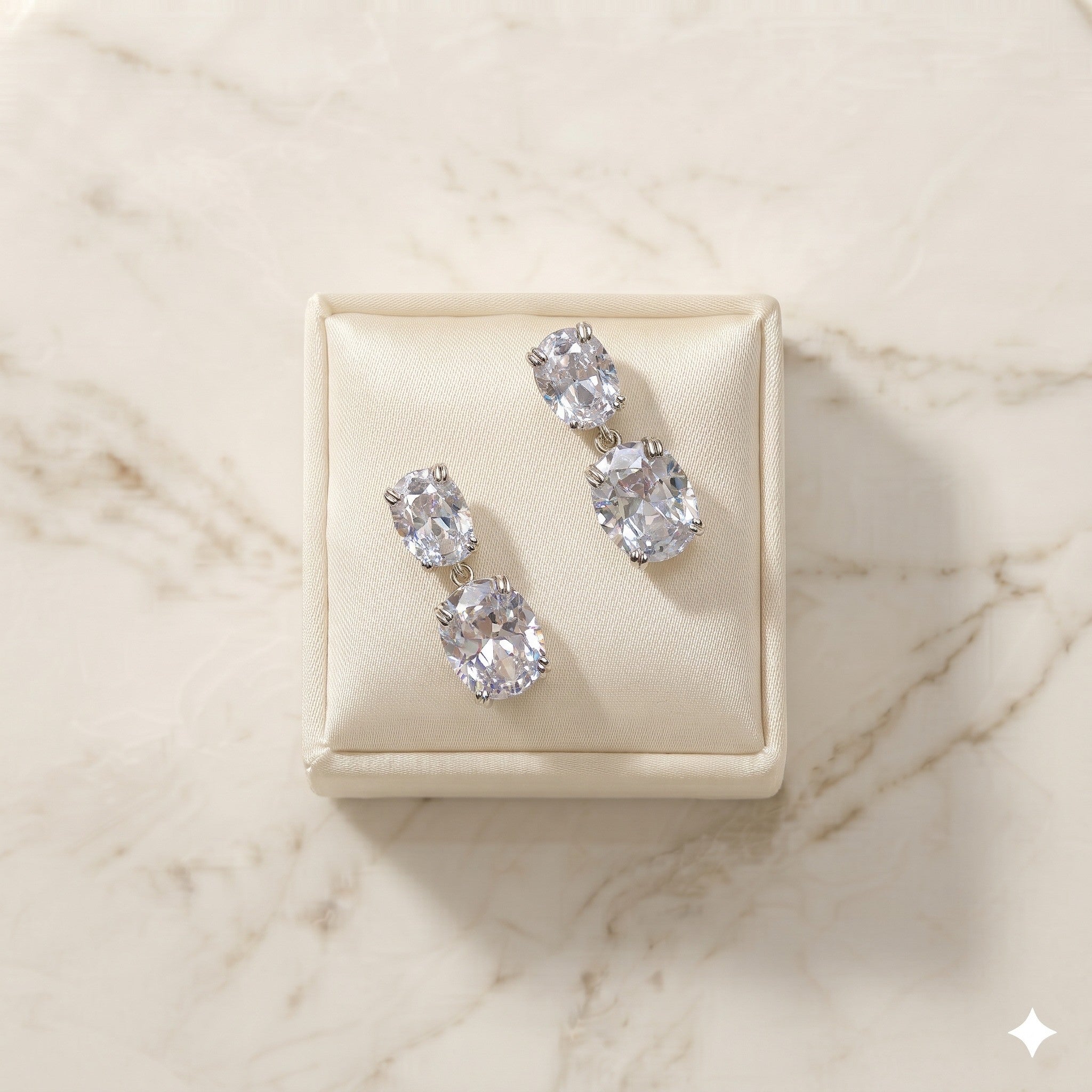 Pair of Josephine silver-finish two-stone drop earrings on a cream jewelry display