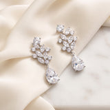 Josie silver-finish bridal earrings with clear marquise leaf clusters and pear-shaped drops on ivory fabric