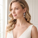 Josie silver-finish leaf drop bridal earrings worn with softly styled waves and an ivory dress