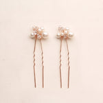 Two complete Mara pearl and crystal hair pins in rose gold.