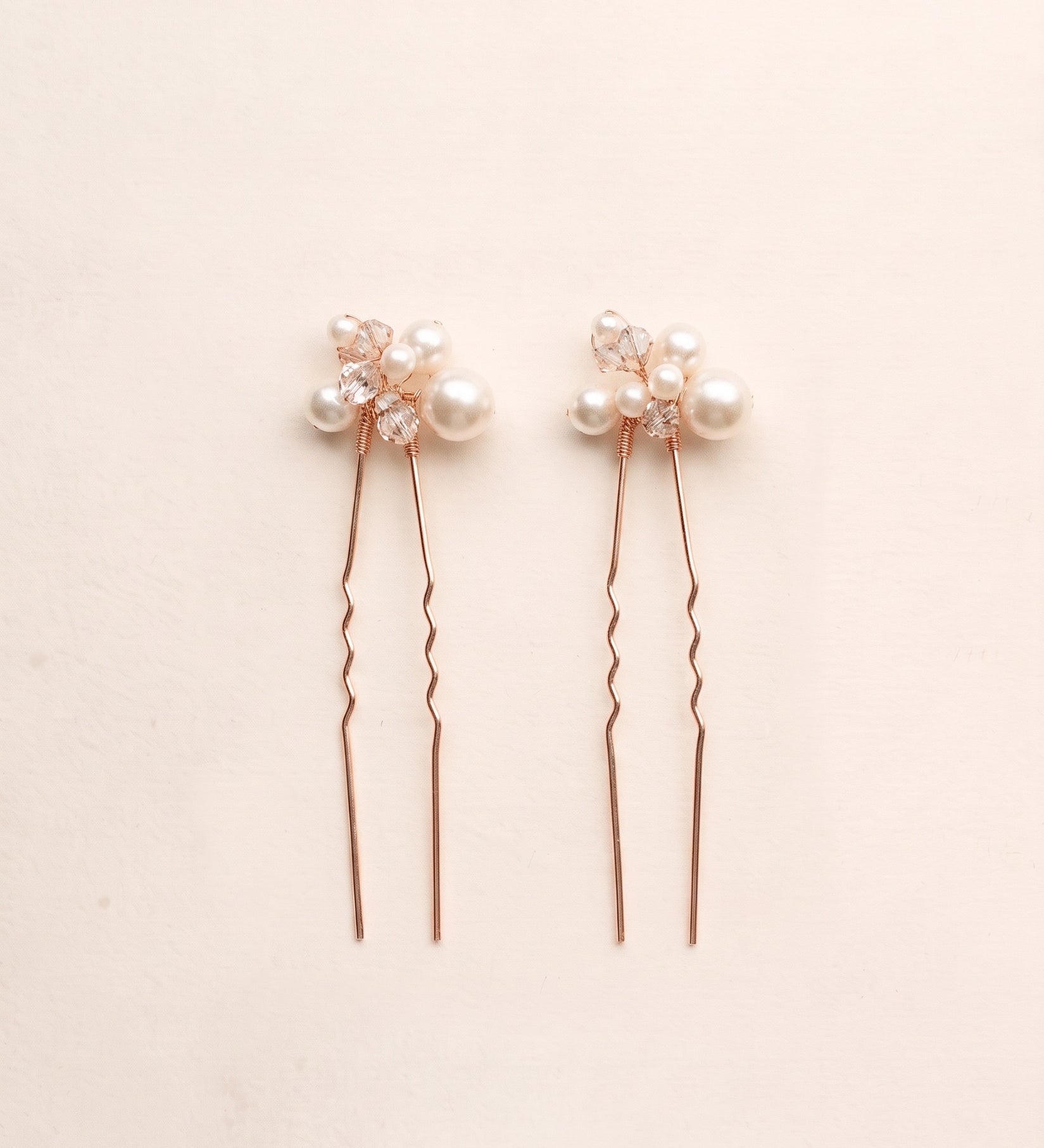 Two complete Mara pearl and crystal hair pins in rose gold.
