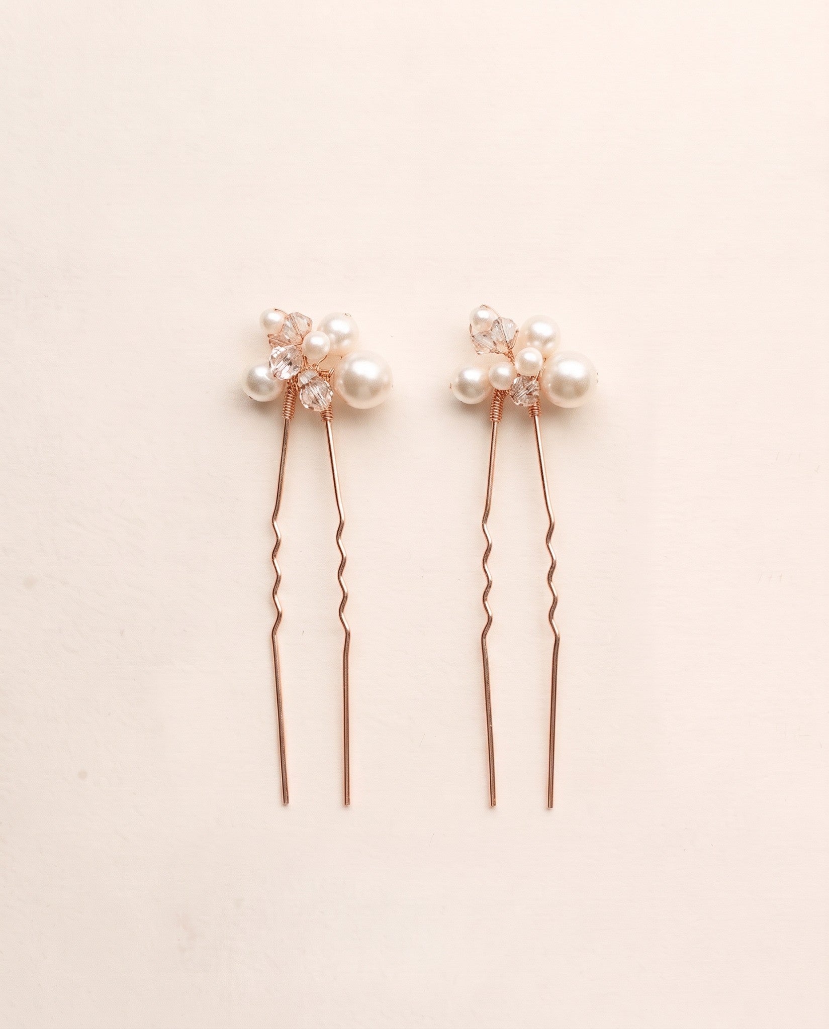 Two complete Mara pearl and crystal hair pins in rose gold.