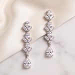 Melody silver cubic zirconia drop earrings displayed on ivory fabric