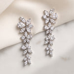 Mia silver-finish cascading floral bridal earrings displayed on ivory fabric and a light surface