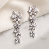 Mia silver-finish cascading floral bridal earrings displayed on ivory fabric and a light surface