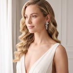 Model wearing Mia silver-finish floral cascade bridal earrings with a white gown