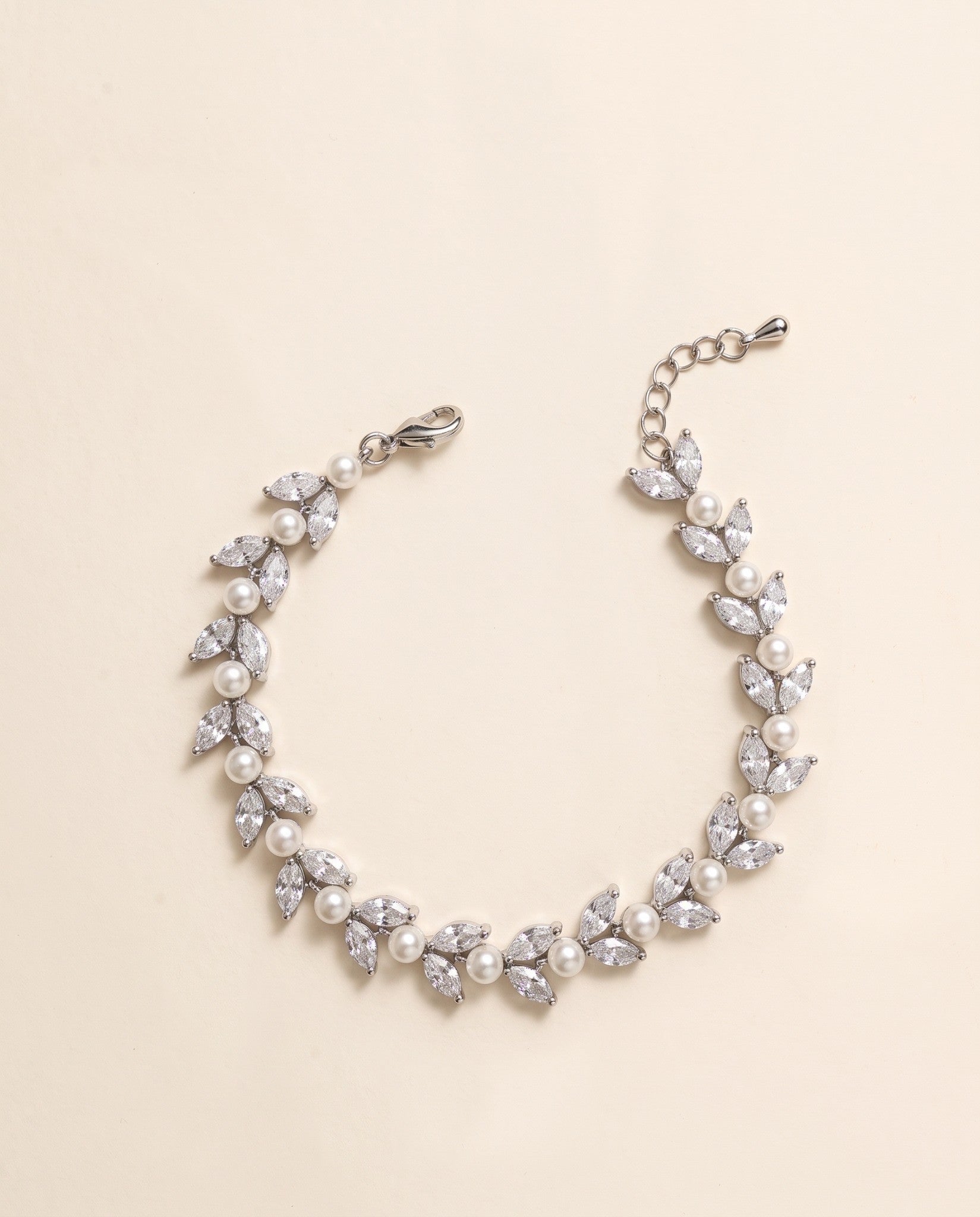 Miranda silver-finish bracelet arranged in a curve, showing paired leaf-shaped accents, round pearl-like details, lobster clasp and extension chain