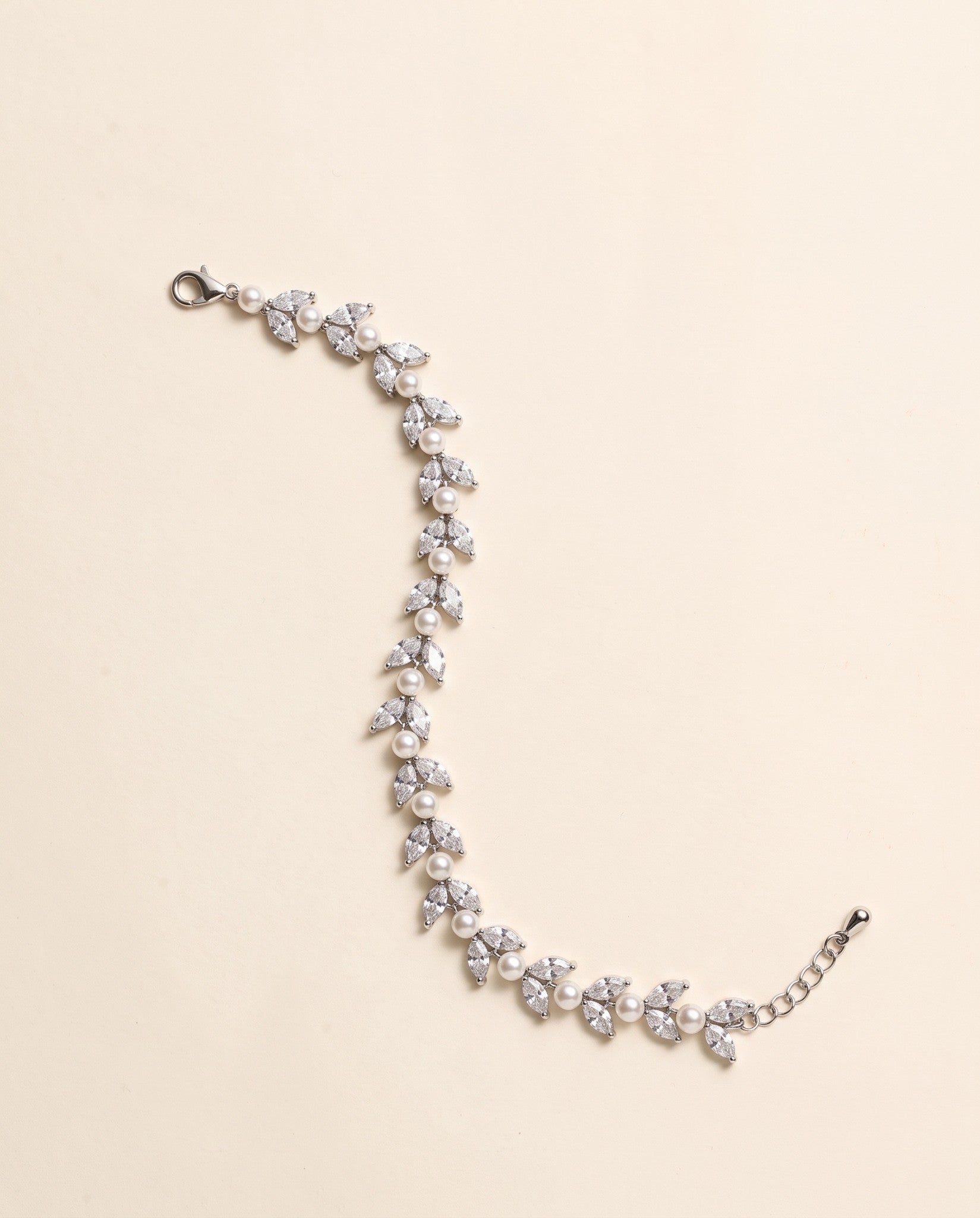 Miranda silver-finish bracelet with paired clear marquise-shaped leaves and round pearl-like accents, shown full length on a cream background