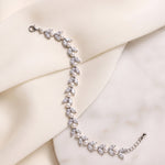 Miranda silver-finish leaf bracelet laid across cream fabric and a pale stone surface