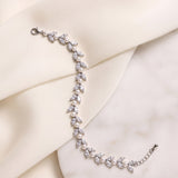 Miranda silver-finish leaf bracelet laid across cream fabric and a pale stone surface