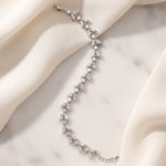 Vivienne silver-finish leaf bracelet arranged across cream fabric and a pale stone surface