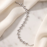 Vivienne silver-finish leaf bracelet arranged across cream fabric and a pale stone surface